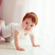 A toddler crawling out of a low bed.