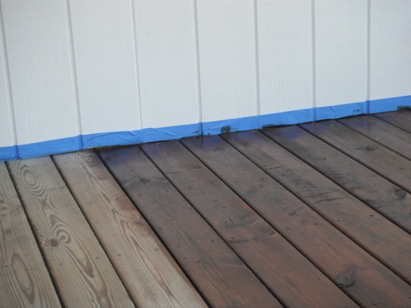 A blue line of painter's tape to protect the wall when staining a deck.
