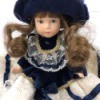 Identifying a Porcelain Doll - doll wearing a white lace dress with a dark blue jacket and matching hat