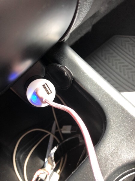 A car phone charger adapter with the light on.