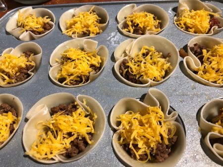 sprinkling Taco Cups with cheese