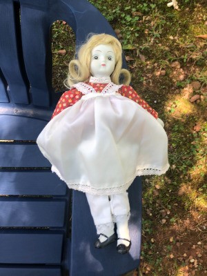 Identifying a Porcelain Doll - doll wearing a red print dress with a white pinafore over it