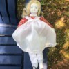 Identifying a Porcelain Doll - doll wearing a red print dress with a white pinafore over it