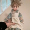 Identifying a Porcelain Doll - doll wearing a floral dress with an off white apron