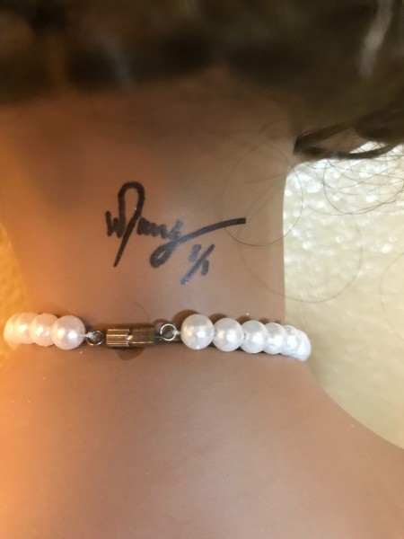 A signature on the back of a porcelain doll.