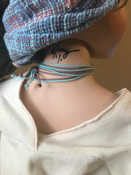 A signature on the back of a porcelain doll.