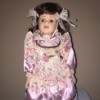 Identifying a Porcelain Doll - doll wearing a lavender dress with floral bodice, part of the sleeves, and an apron like layer