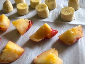 Fruit slices on parchment paper to be frozen individually.