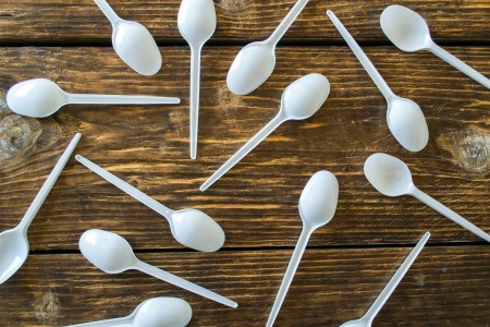 A collection of plastic spoons on a wooden table.
