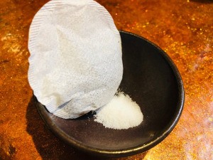 A tea bag in a bowl with some salt.