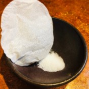 A tea bag in a bowl with some salt.