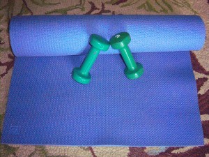 An exercise mat and a pair of dumbbells for exercising.