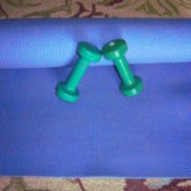 An exercise mat and a pair of dumbbells for exercising.
