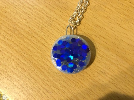 Making a Bottle Cap Glitter Pendant Necklace - add craft glue to the surface of the cap and sprinkle on large glitter