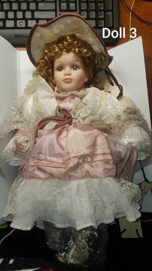 Identifying Porcelain Dolls  - curly haired doll wearing a pink dress with white lace
