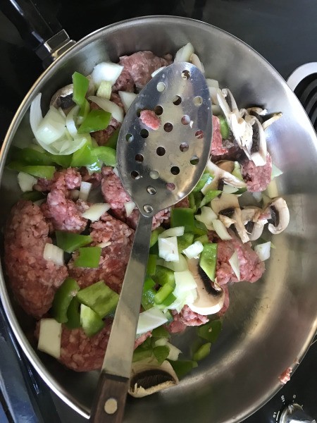 ground beef with cut peppers & onions in skillet