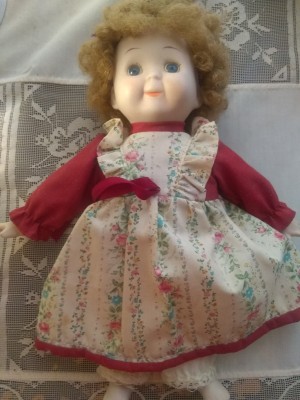 Identifying a Porcelain Doll - cute doll wearing a red dress with a floral pinafore look to it
