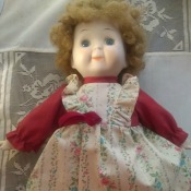 Identifying a Porcelain Doll - cute doll wearing a red dress with a floral pinafore look to it