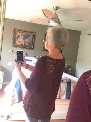 Dyeing Grey Hair - woman taking her photo backwards in a mirror to show back of head