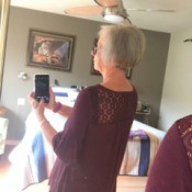 Dyeing Grey Hair - woman taking her photo backwards in a mirror to show back of head