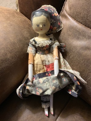 Identifying a Vintage Carved Wooden Doll - doll wearing a patchwork dress and a bonnet that is pulled back in this photo