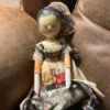 Identifying a Vintage Carved Wooden Doll - doll wearing a patchwork dress and a bonnet that is pulled back in this photo