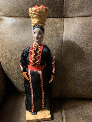 Maker of Beautiful Vintage Israeli Doll - doll wearing a long black dress with vertical decorations and carrying a basket on her head