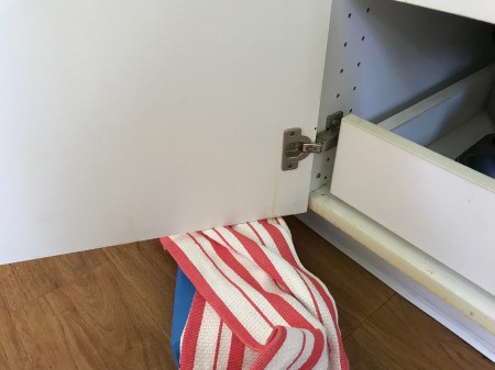 A cabinet hinge being held up with a yoga block.