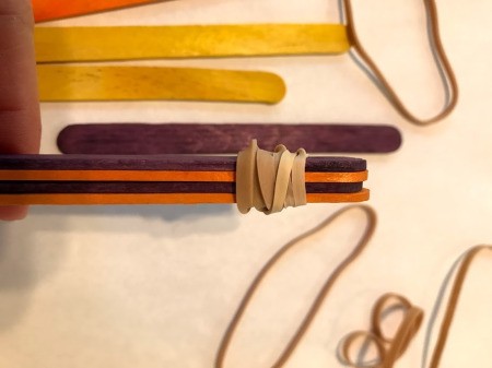 Making a Craft Stick Catapult for Kids - wrap each end tightly with the bands