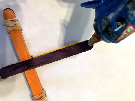 Making a Craft Stick Catapult for Kids - add hot glue to the end of the single stick