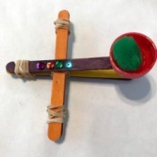 Making a Craft Stick Catapult for Kids - catapult loaded with a green pom pom