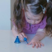 A little girl putting on nail polish.