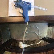 Stop Hot Glue from Slipping Off Table - glue gun attached to an extension cord wrapped around chair back