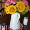 Zinnias and sunflowers in a white pitcher.