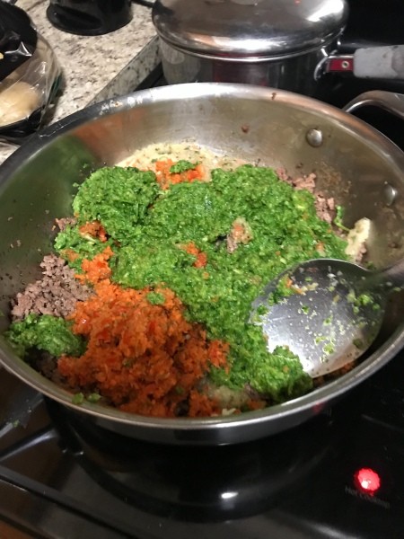 Adding finely chopped vegetables to ground beef mixture.