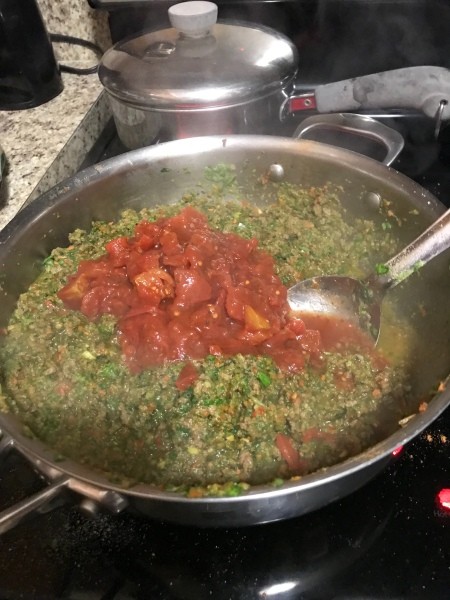 Adding tomatoes to ground beef mixture.
