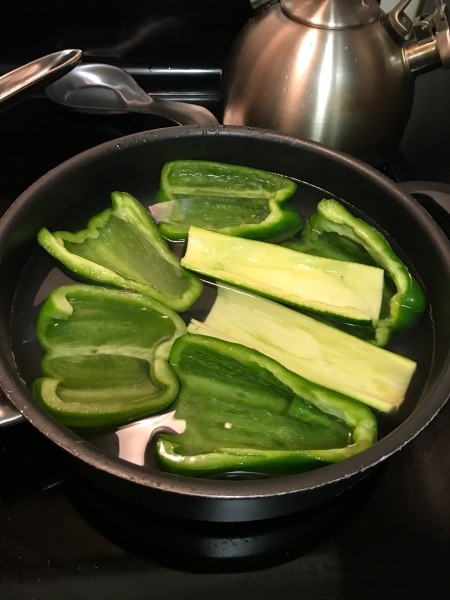 Parboiling zucchini and pepper halves.