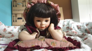 Identifying a Porcelain Doll - doll in gingham dress lying on tummy and propped up on elbows