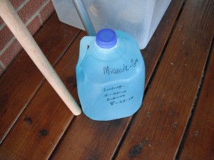 Remembering When to Feed My Plants - milk jug of Miracle Gro on porch, with dates written on the bottle as a reminder