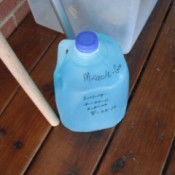 Remembering When to Feed My Plants - milk jug of Miracle Gro on porch, with dates written on the bottle as a reminder