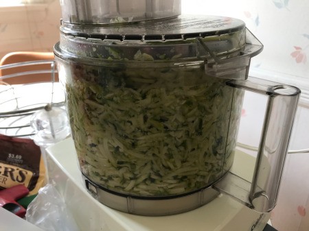 A food processor full of shredded zucchini.