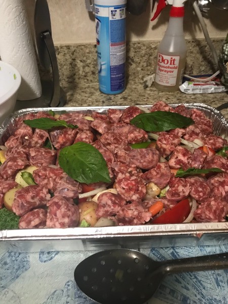 sausage on top of veggies in baking pan