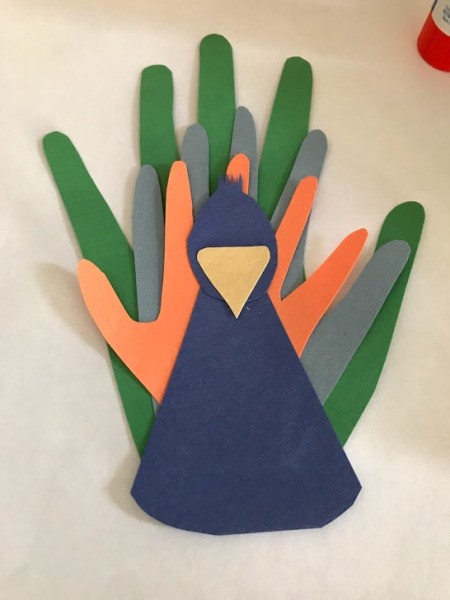Peacock Popsicle Stick Puppet - body, head, and beak assembly glued to handprint cut outs (feathers)