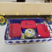 Several containers stored in a wire basket that pushes under the microwave.