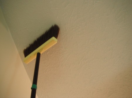 Cleaning a Bedroom By Yourself - dusting ceiling with a broom