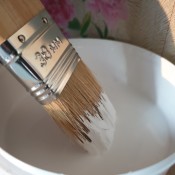 A paintbrush in a bucket of white paint.