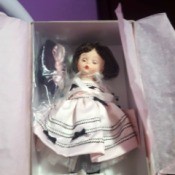 Value of a Madame Alexander Doll -  small doll with closable eyes wearing a white dress with dark trim and bows