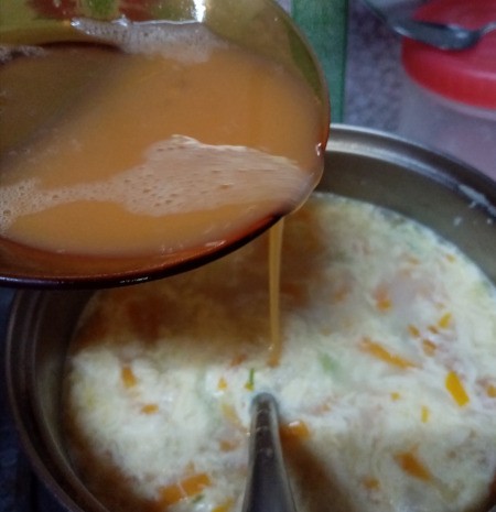 slowly adding egg to soup