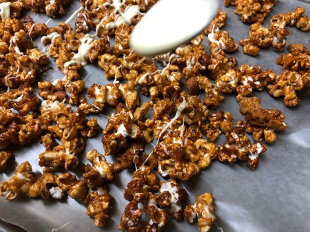 spooning White Chocolate on Caramel Popcorn & nuts
