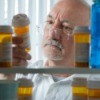 A man looking at his prescriptions in a medicine cabinet.
